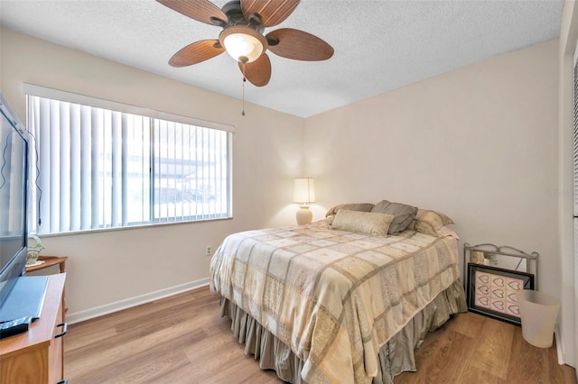 bedroom with light hardwood / wood-style flooring, a textured ceiling, and ceiling fan