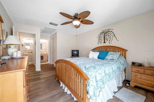 bedroom with connected bathroom, ceiling fan, wood-type flooring, and a textured ceiling