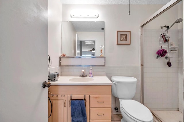 bathroom with a shower with door, a textured ceiling, tile walls, toilet, and vanity