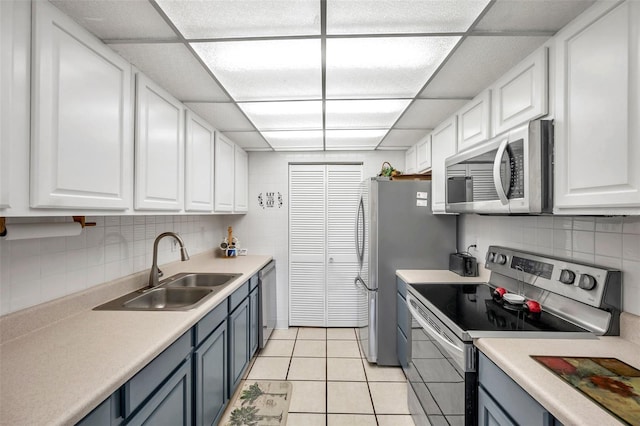 kitchen with sink, appliances with stainless steel finishes, light tile patterned floors, and white cabinets