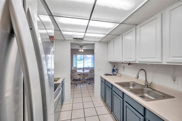 kitchen with white cabinetry, blue cabinets, sink, and stainless steel refrigerator