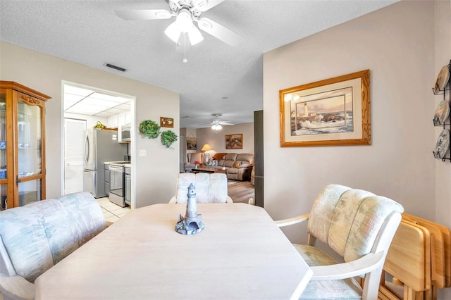 tiled dining room with ceiling fan and a textured ceiling