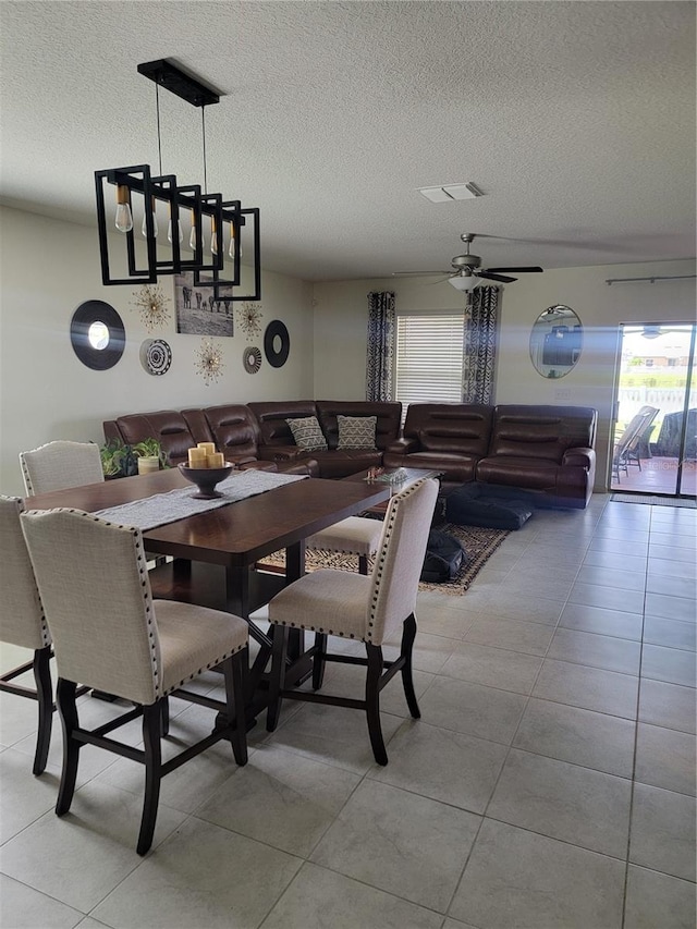 tiled dining space with a textured ceiling and ceiling fan