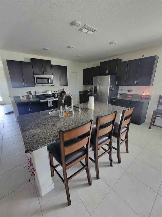 kitchen with appliances with stainless steel finishes, an island with sink, and a breakfast bar