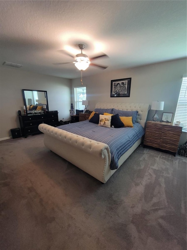 bedroom with ceiling fan, a textured ceiling, and dark carpet