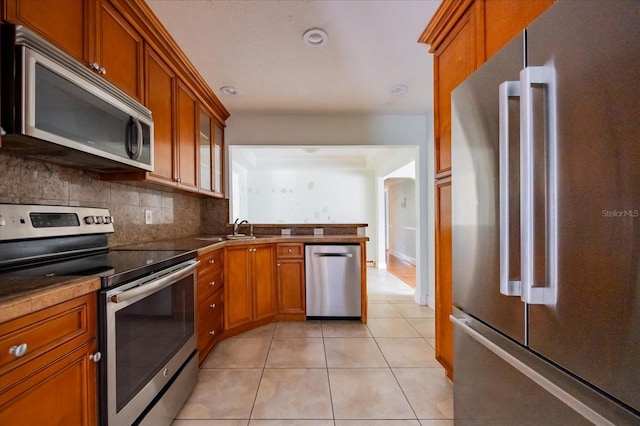 kitchen with stainless steel appliances, light tile patterned flooring, tasteful backsplash, and sink