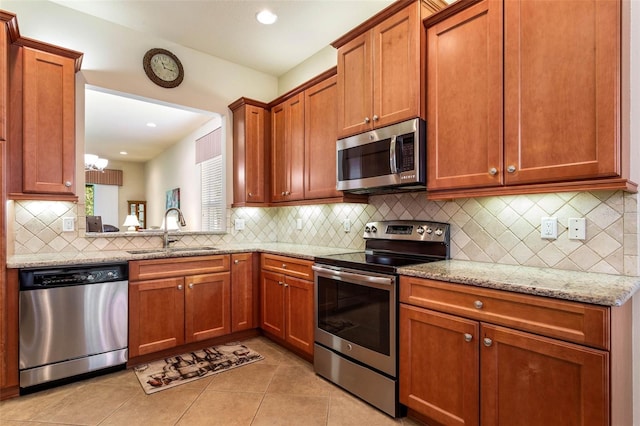 kitchen featuring backsplash, light stone countertops, light tile patterned floors, stainless steel appliances, and sink