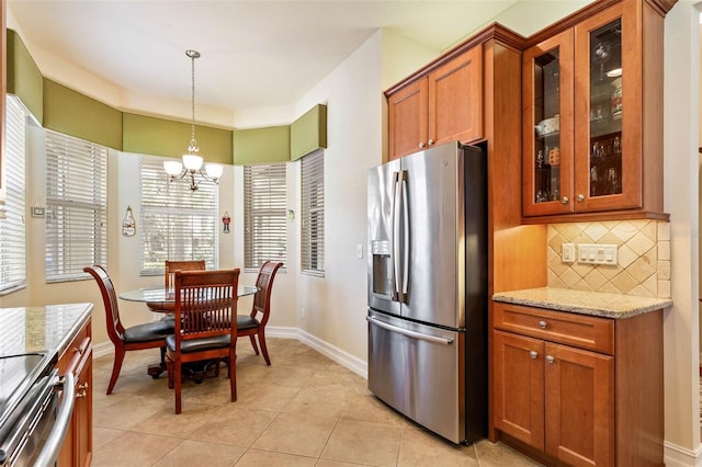 kitchen with light tile patterned flooring, tasteful backsplash, stainless steel appliances, decorative light fixtures, and light stone countertops