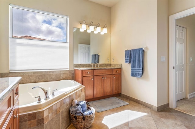 bathroom with tiled tub, vanity, and tile patterned flooring