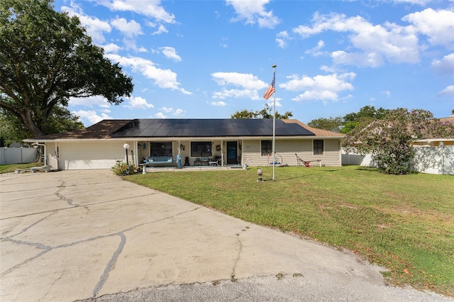 ranch-style home with solar panels, a front yard, and a garage