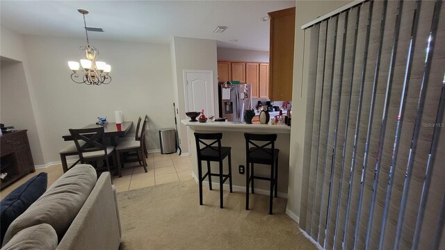 interior space featuring stainless steel refrigerator with ice dispenser, light tile patterned flooring, a chandelier, and hanging light fixtures