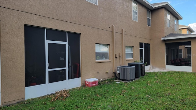 rear view of property featuring cooling unit, a yard, and a sunroom