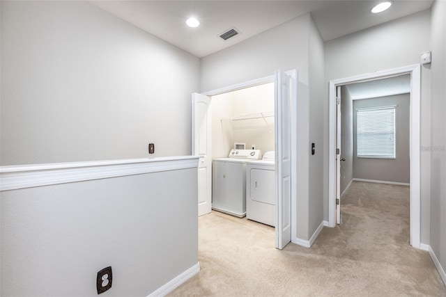 washroom featuring washer and clothes dryer and light colored carpet