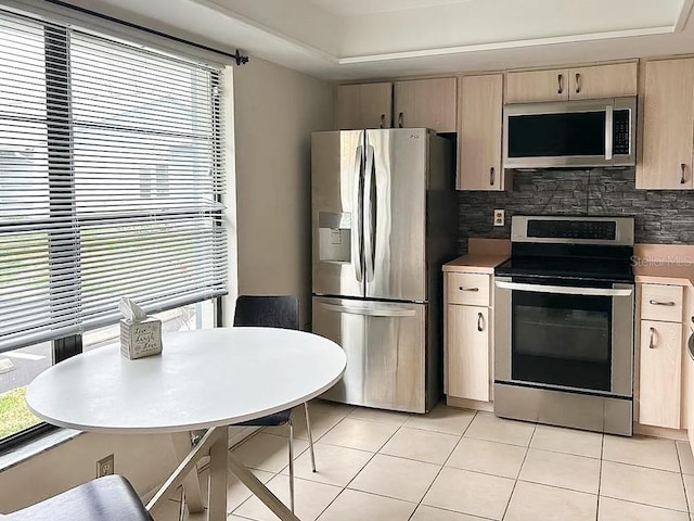 kitchen with appliances with stainless steel finishes, plenty of natural light, and light tile patterned floors