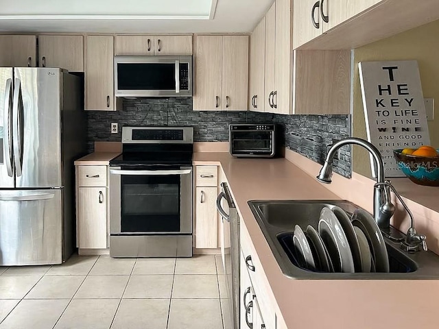 kitchen featuring light tile patterned floors, stainless steel appliances, sink, and decorative backsplash