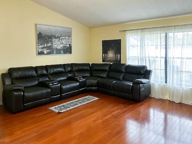 living room featuring wood-type flooring, vaulted ceiling, and a textured ceiling