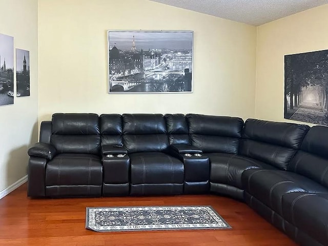 living room featuring wood-type flooring, a textured ceiling, and vaulted ceiling