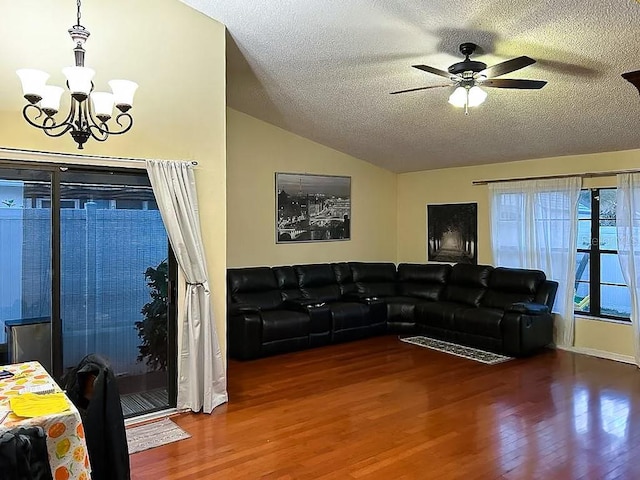 living room with hardwood / wood-style flooring, ceiling fan with notable chandelier, vaulted ceiling, and a textured ceiling