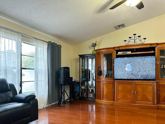 living room featuring a textured ceiling, dark hardwood / wood-style floors, and ceiling fan