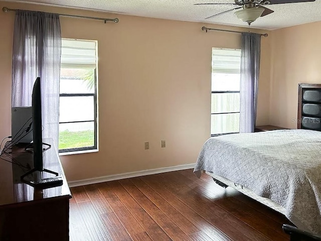 bedroom with multiple windows, ceiling fan, dark hardwood / wood-style floors, and a textured ceiling