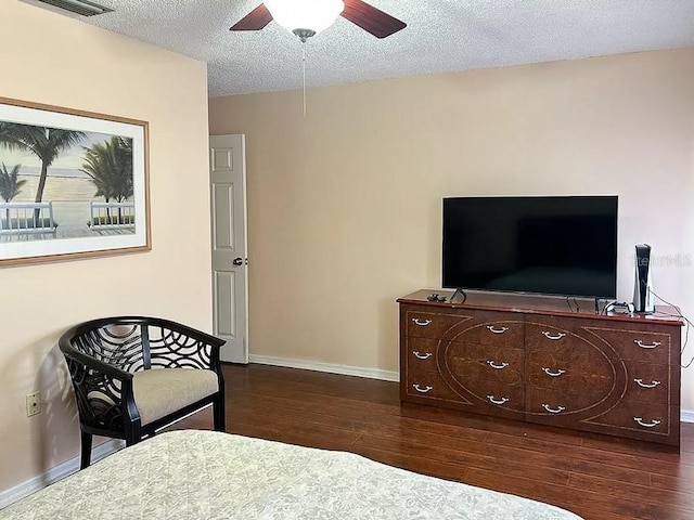 bedroom with a textured ceiling, ceiling fan, and dark hardwood / wood-style flooring