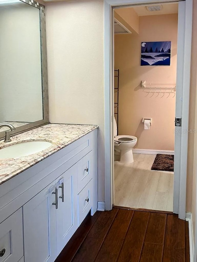 bathroom featuring vanity, hardwood / wood-style floors, and toilet