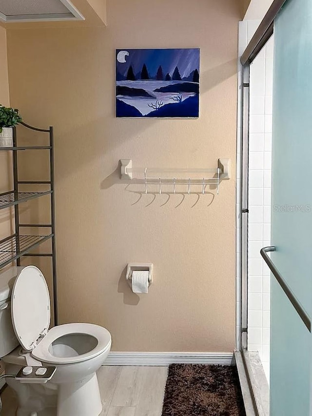 bathroom with wood-type flooring, toilet, and an enclosed shower