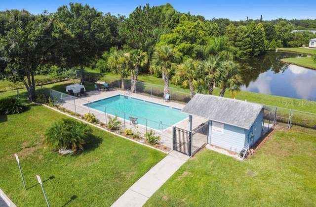 view of pool with an outdoor structure, a yard, and a water view