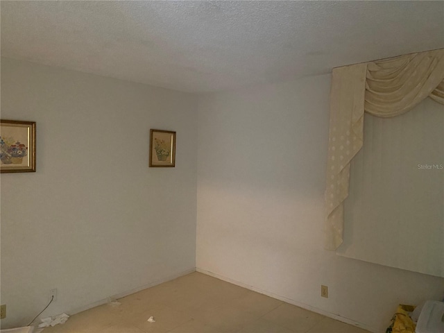 spare room featuring baseboards and a textured ceiling