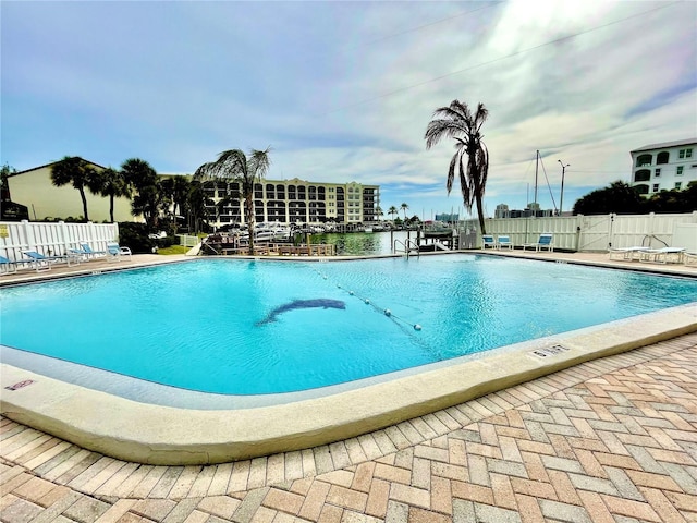 community pool with a patio and fence