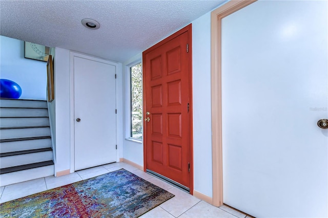 foyer entrance featuring a textured ceiling and light tile patterned floors