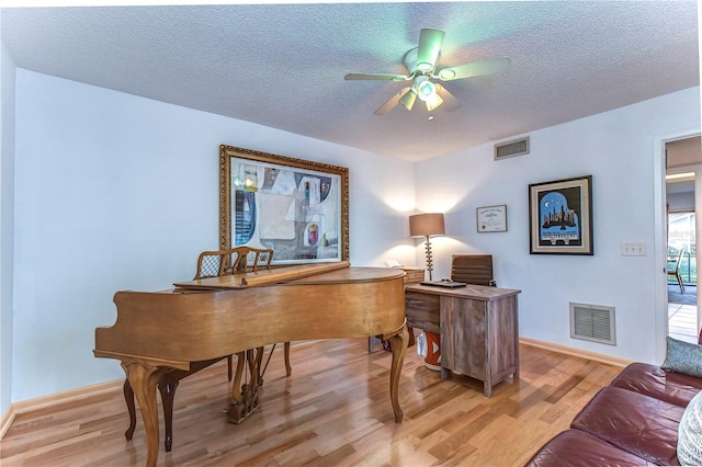 office featuring light wood-type flooring, ceiling fan, and a textured ceiling