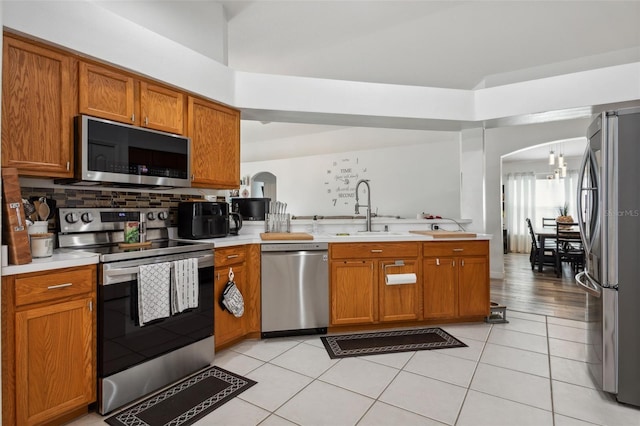 kitchen with stainless steel appliances, light hardwood / wood-style floors, kitchen peninsula, and sink