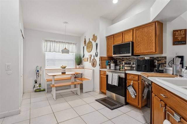 kitchen featuring decorative backsplash, stainless steel appliances, hanging light fixtures, and light tile patterned flooring