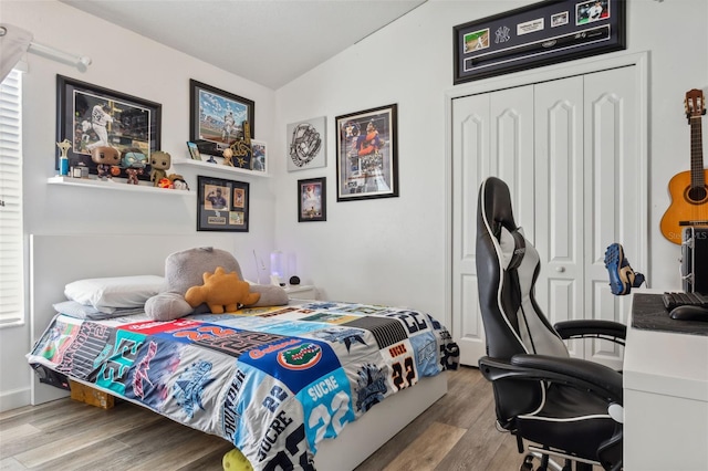 bedroom with light hardwood / wood-style floors, vaulted ceiling, and a closet