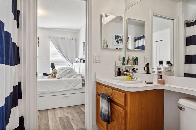 bathroom with wood-type flooring, vanity, and toilet