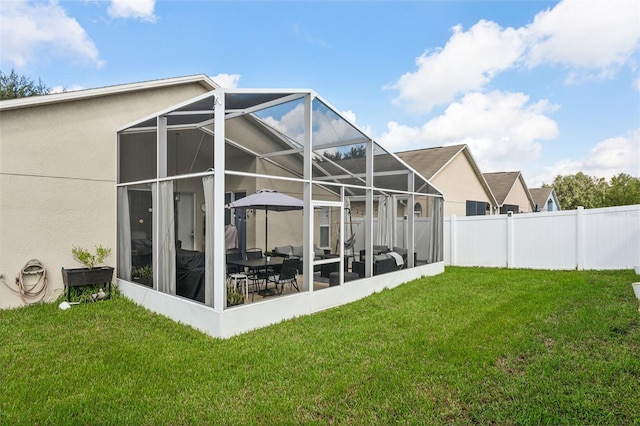 rear view of property with a patio, a yard, and a lanai