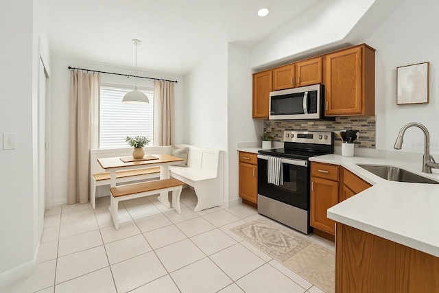 4206 Branchside Ln, Wesley Chapel, FL 33543 - kitchen featuring appliances with stainless steel finishes, brown cabinetry, decorative backsplash, light countertops, and hanging light fixtures