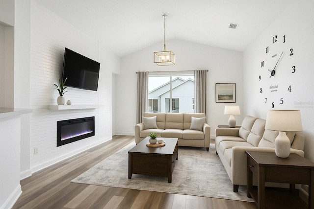 4206 Branchside Ln, Wesley Chapel, FL 33543 - living room featuring wood finished floors, lofted ceiling, a large fireplace, and a chandelier