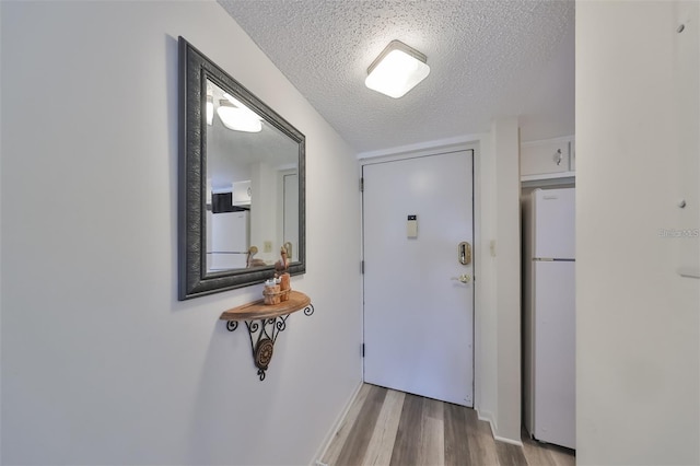 entryway with light wood-type flooring and a textured ceiling