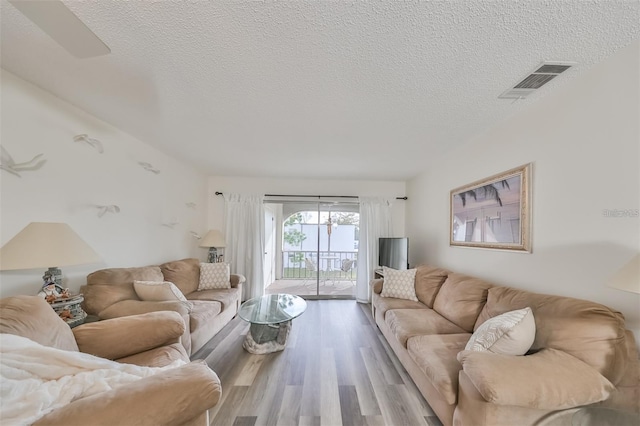 living room with a textured ceiling and light hardwood / wood-style flooring