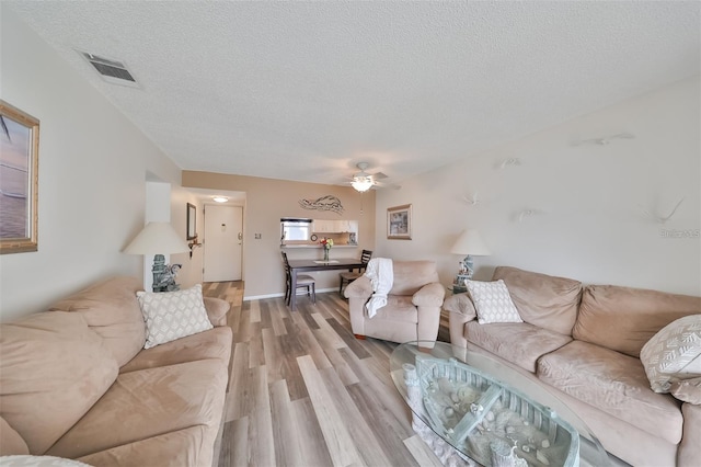 living room featuring a textured ceiling, wood-type flooring, and ceiling fan