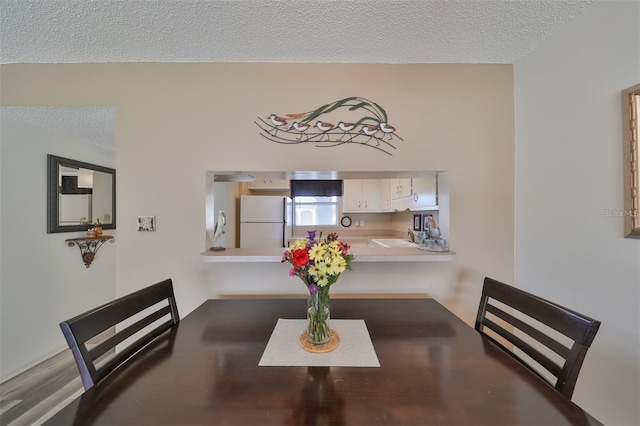 dining space with a textured ceiling, sink, and hardwood / wood-style flooring