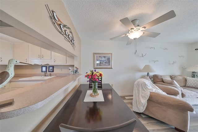 dining space featuring light wood-type flooring, a textured ceiling, and ceiling fan