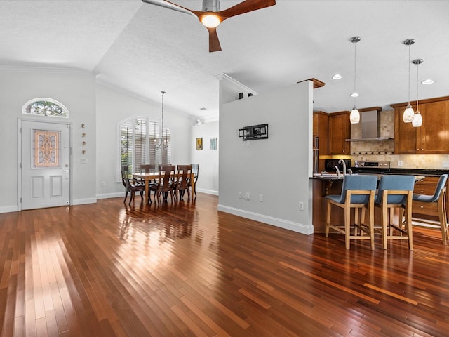 dining space featuring a textured ceiling, dark wood-type flooring, ceiling fan with notable chandelier, vaulted ceiling, and ornamental molding