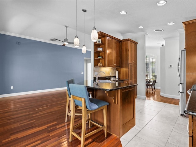 kitchen featuring ornamental molding, light wood-type flooring, decorative light fixtures, and sink