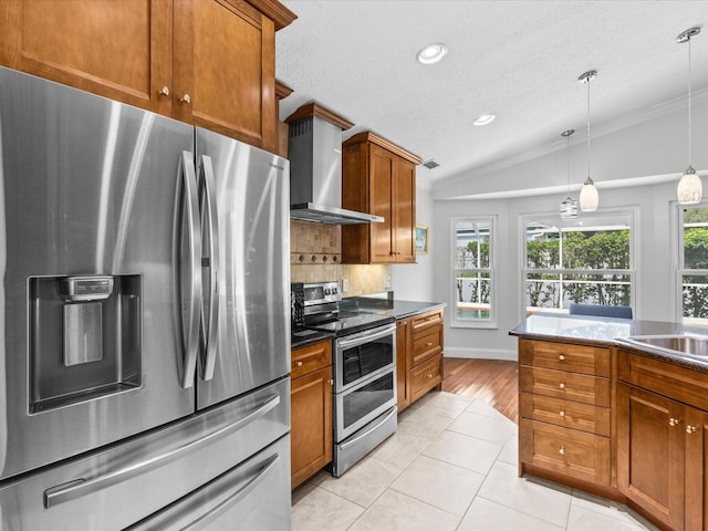 kitchen with wall chimney exhaust hood, light tile patterned floors, stainless steel appliances, a textured ceiling, and lofted ceiling