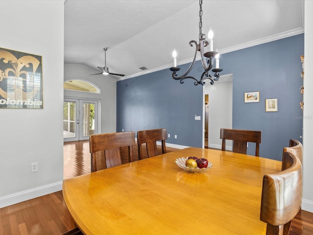 dining space with ceiling fan with notable chandelier, wood-type flooring, lofted ceiling, and crown molding