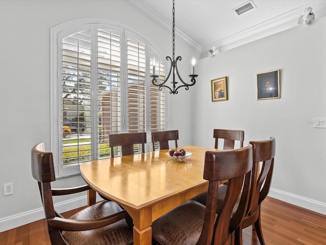 dining room with crown molding, dark hardwood / wood-style floors, and a chandelier