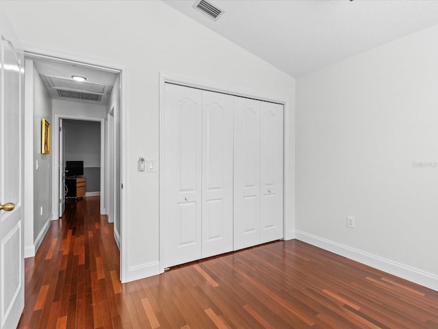 unfurnished bedroom featuring lofted ceiling, a closet, and dark hardwood / wood-style floors